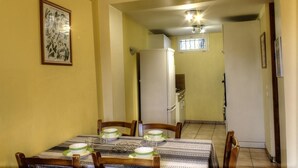 A dining area with a table set for four, a refrigerator in the background, and a framed artwork on the wall. - Saint-Roch - PEILLE - Gîte (PEILLE)