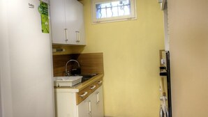 A compact kitchen with white cabinets, a sink, and a window with bars. - Saint-Roch - PEILLE - Gîte (PEILLE)