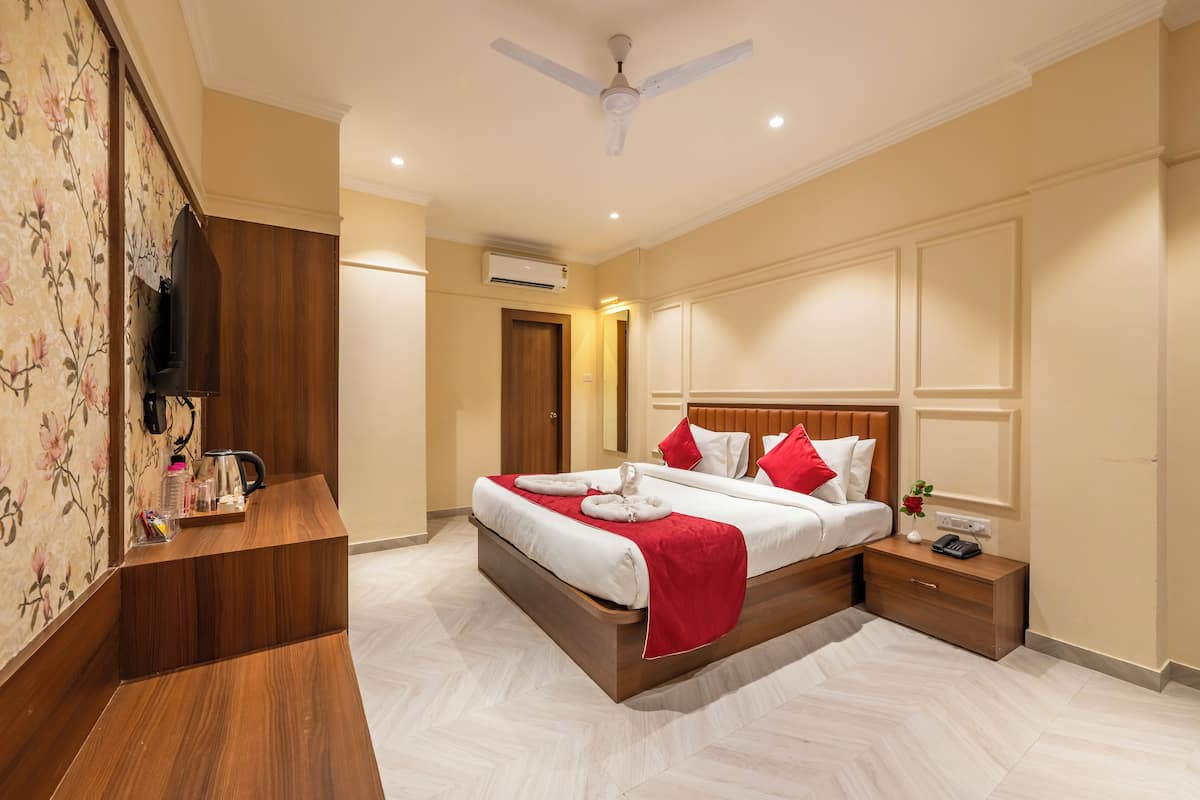 A hotel room with a bed, wooden nightstand, and a ceiling fan.