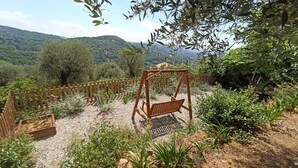 Ein Garten mit einer hölzernen Schaukel, Kieswegen und verschiedenen Pflanzen.