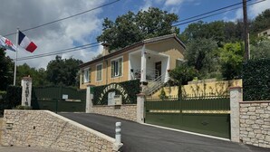 A two-story building with a stone wall entrance, a green gate, and a sign reading 'LA FERME RIOLA'. - Riola Farm - Gîte n°6004 (Contes)