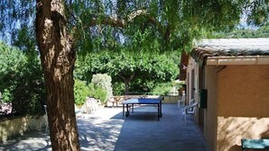 A courtyard with a ping pong table, outdoor seating, and a building with a tiled roof. - Riola Farm - Gîte n°6004 (Contes)