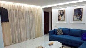 A modern living room with a blue sofa, a round coffee table, and a patterned rug. - Luxury Villa Hay Ryad (Rabat)