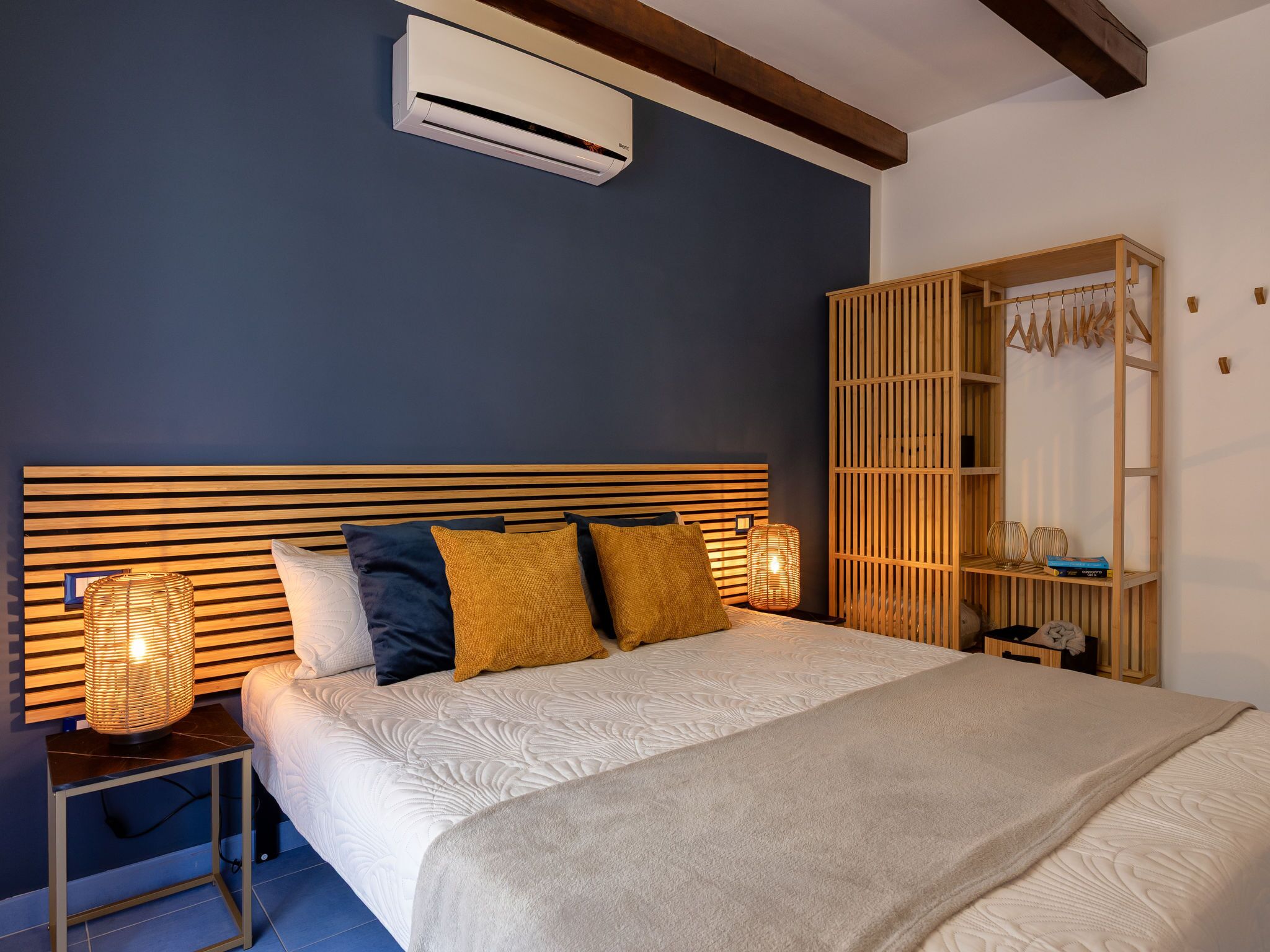 Una camera da letto con un letto, abat-jour, un armadio e un condizionatore d'aria.