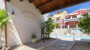 A covered outdoor area with a pool, labeled 'RESIDENCE Li Duni', surrounded by stone tiles and potted plants. - Luce del Mare by Interhome (Valledoria)