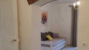 A room with a bed, a small table, and a painting on the wall. - Romarin - EZE - Gîte (EZE)