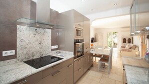 Een moderne keuken met granieten aanrechtbladen, roestvrijstalen apparatuur en een glazen spatwand.