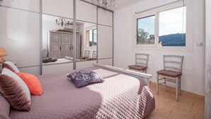 Een slaapkamer met een groot bed, een spiegel, twee stoelen en een raam met uitzicht.