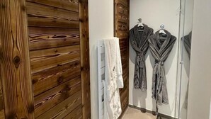 Un baño con paneles de madera, un perchero blanco y dos batas colgadas en un perchero.