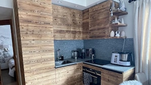 Una cocina moderna con armarios de madera, horno empotrado y cafetera.
