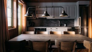 Une cuisine moderne avec une grande table en bois, six chaises et des luminaires suspendus.