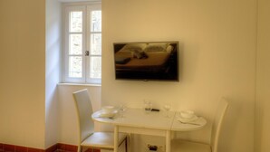 A small dining area with a table, chairs, and a television mounted on the wall.