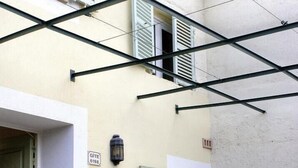 A building with a balcony, a door, and a table with chairs. - Espace des Oliviers - Gîte n°2 (CASTAGNIERS)