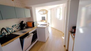 A compact kitchen with a dishwasher, oven, and a small dining area with a table and chairs.