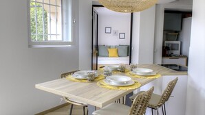 A dining area with a wooden table set for four, surrounded by wicker chairs.