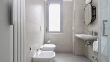 A modern bathroom with two toilets, a bidet, a sink, and a mirror.