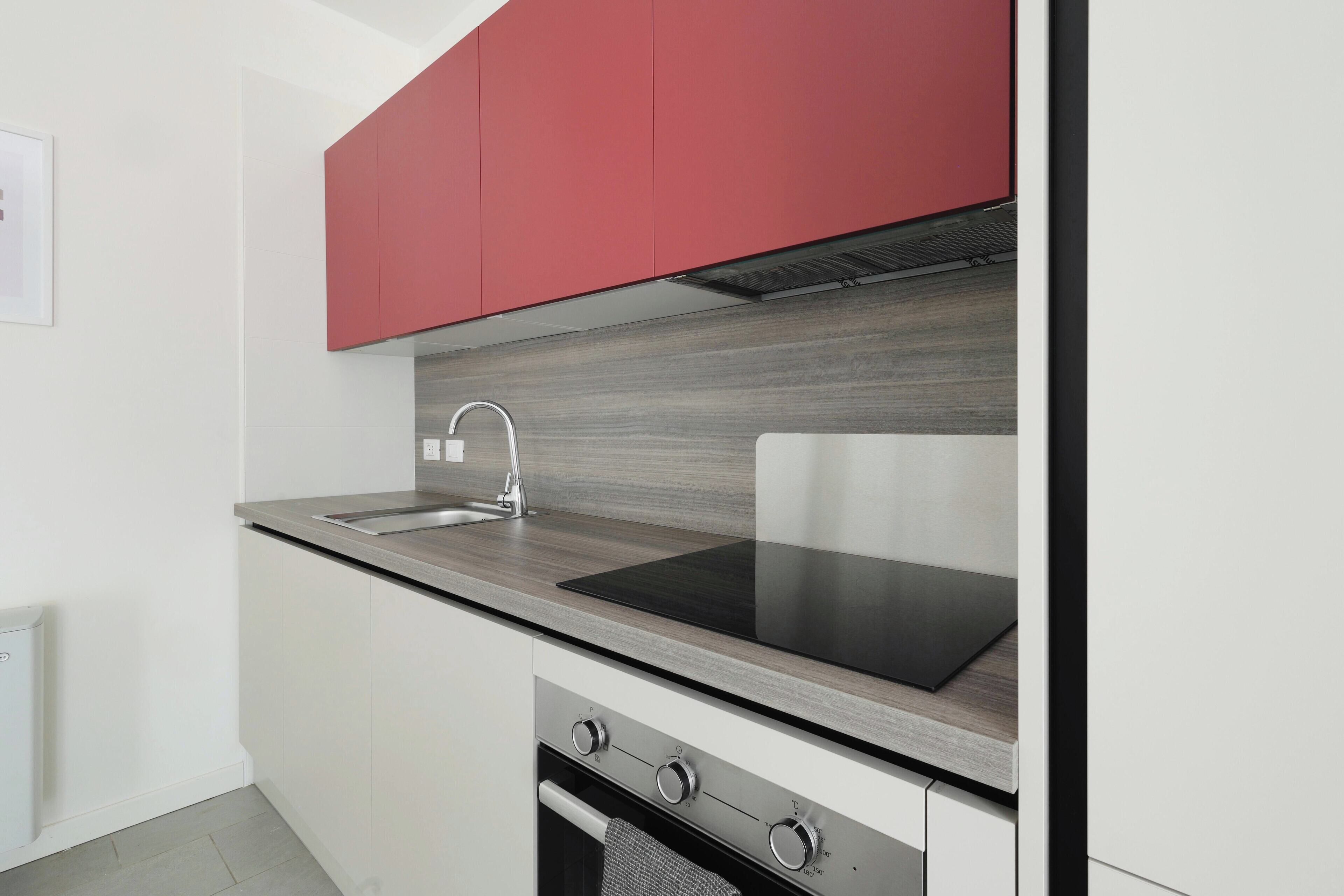 A modern kitchen with a stainless steel sink, a black induction cooktop, and a built-in oven.