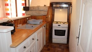Una cocina pequeña con pileta, estufa y alacenas.
