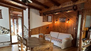 Un intérieur chaleureux en bois, avec une table et des chaises, un canapé à carreaux et un mur en pierre.
