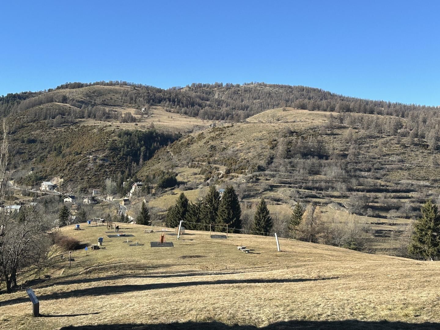Un paysage vallonné avec un petit village, comprenant des maisons et un terrain de jeux.