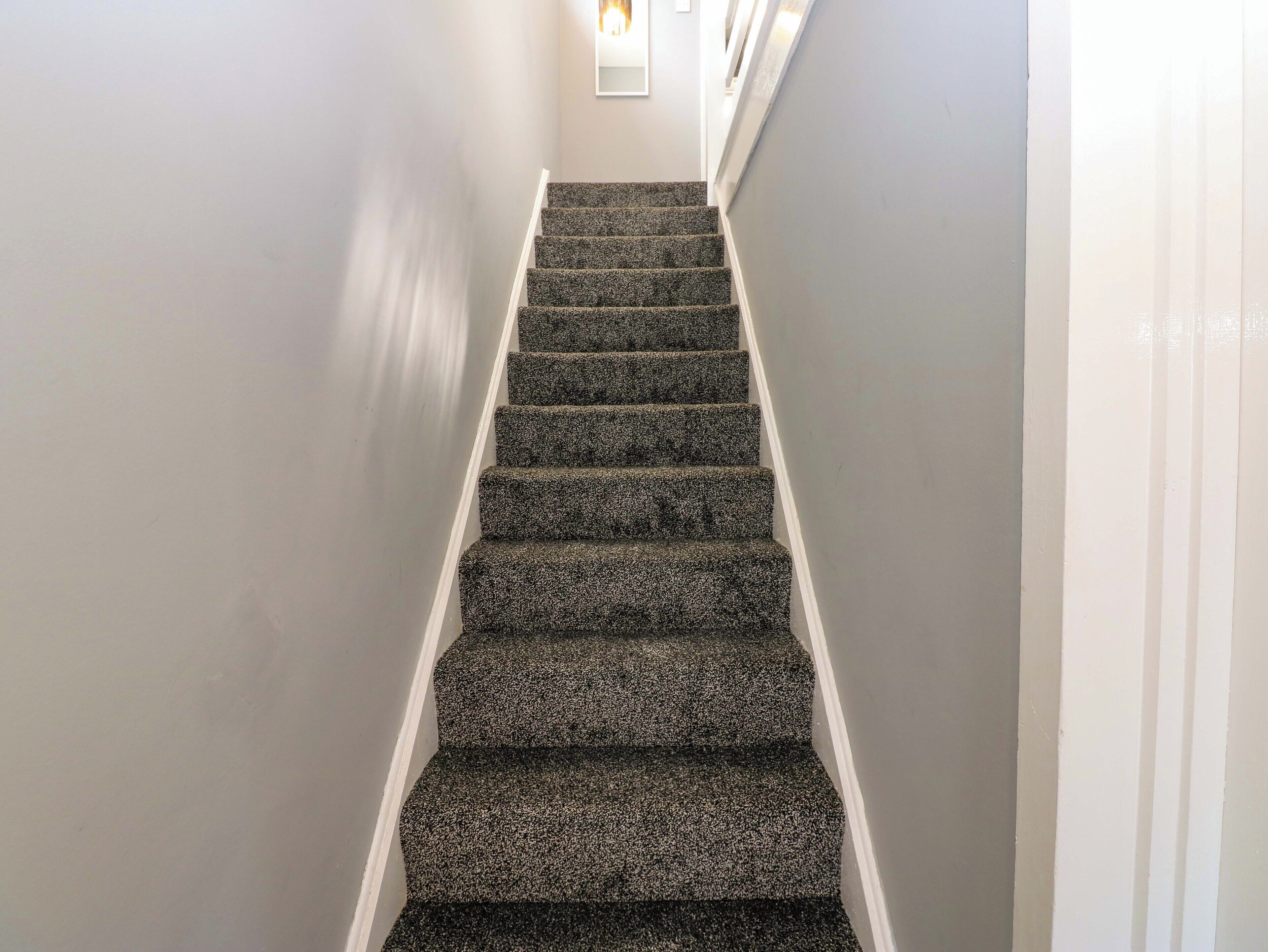 A staircase with carpeted steps and white walls.