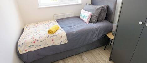 Un petit lit bien fait, avec une couverture à motifs floraux et une serviette enroulée.