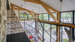 A modern interior with exposed wooden beams, a stone wall, and a view of the outdoors.