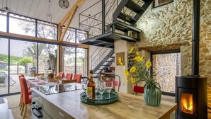 A modern kitchen with a central island, a stone wall, and a fireplace.