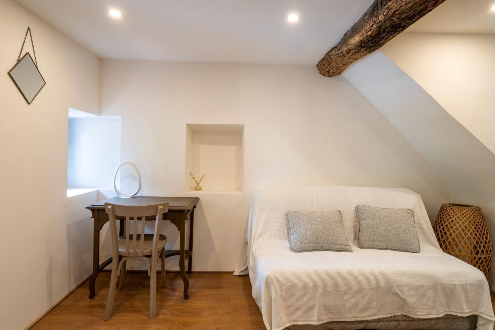 Un dormitorio con cama, escritorio y silla. Una ventana deja entrar luz natural.