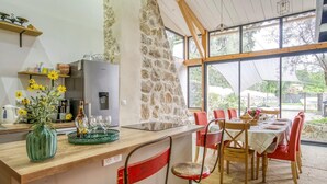 A dining area with a stone wall, wooden beams, and large windows.