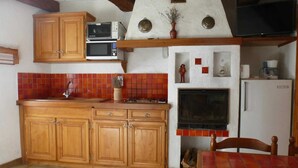 A kitchen with wooden cabinets, a microwave, a stove, a sink, and a refrigerator. - Les Mesanges aux Baux (SERANON)