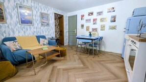 A compact living space with a sofa, a small dining table, and a kitchenette.