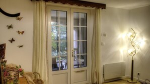 A room with a wooden floor, a white door with glass panels, a table with chairs, a lamp, and butterfly wall decorations.