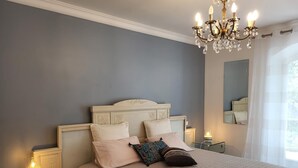 Una camera da letto con un letto grande, un lampadario, lampade sui comodini e uno specchio.