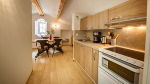 A modern kitchen with wooden cabinets, a built-in oven, and a dining area with a table and chairs.
