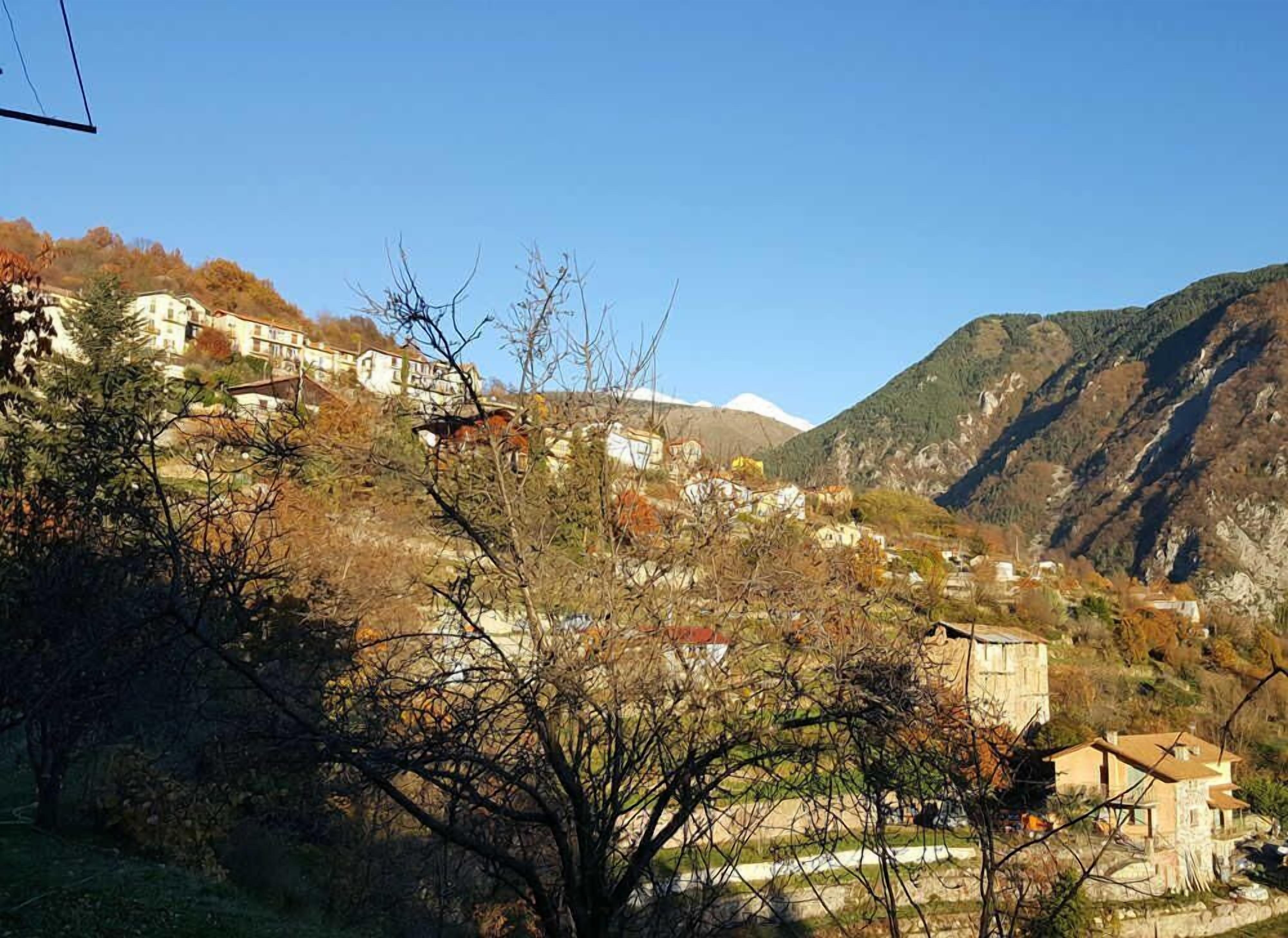 Un village de montagne aux bâtiments traditionnels en pierre, dont certains sont dotés de balcons apparents, et sous un ciel dégagé.