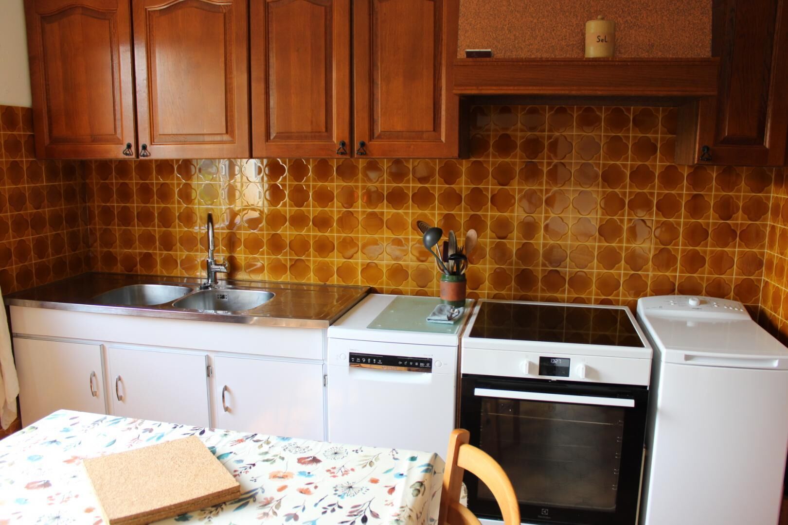 A compact kitchen with wooden cabinets, a double sink, a microwave, and an oven.