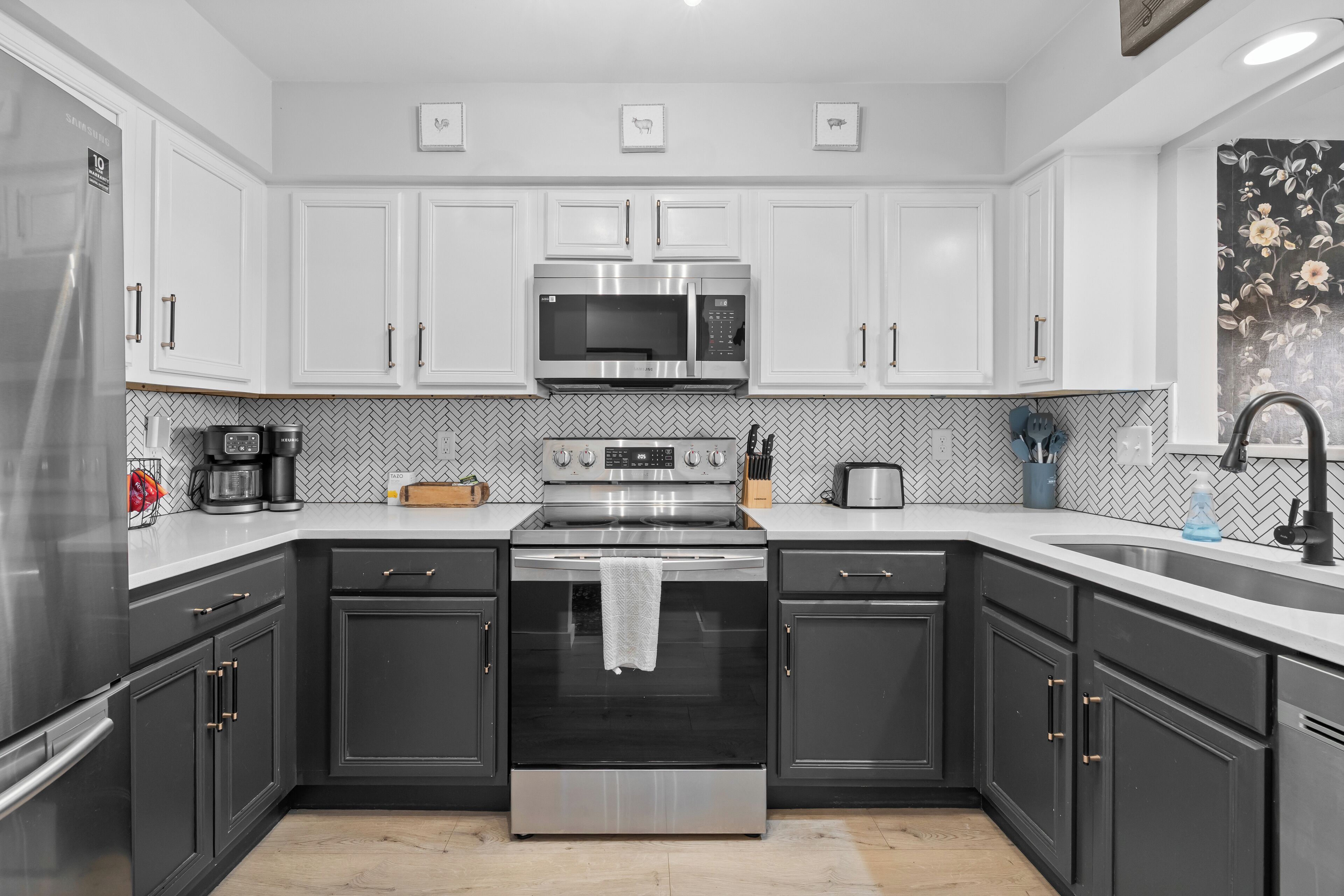Una cocina moderna con armarios blancos, electrodomésticos de acero inoxidable y un salpicadero de azulejos tipo espiga.