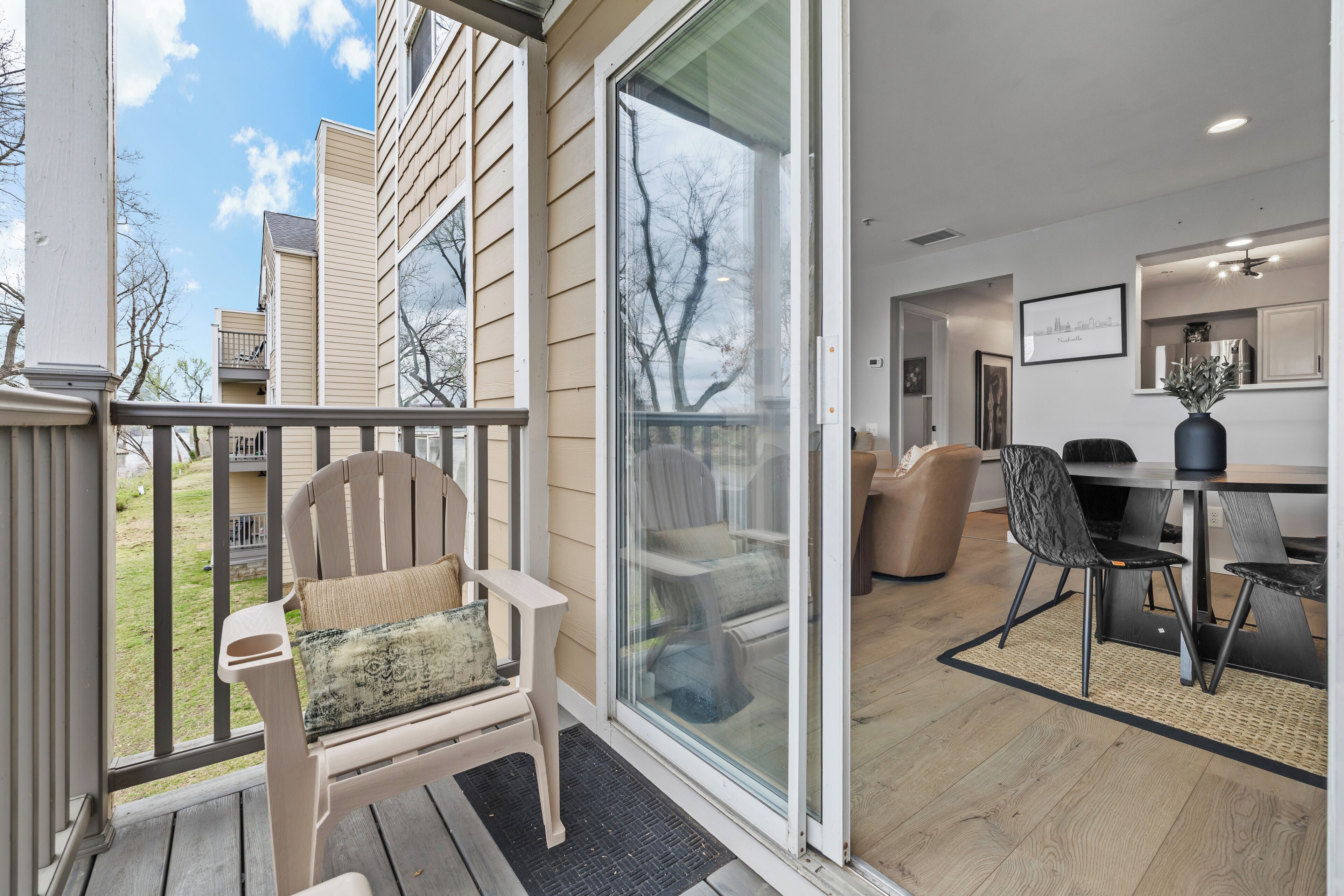 Un salon moderne doté d’une porte vitrée donnant sur un balcon, un coin repas avec une table et des chaises, et une vue sur l’extérieur.