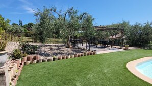 Een achtertuin met een zwembad, een pergola en een verzorgd gazon.