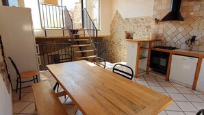 A kitchen with a wooden table, chairs, a stove, and a dishwasher. - Le Ciste - SAINT-JEANNET (SAINT-JEANNET)