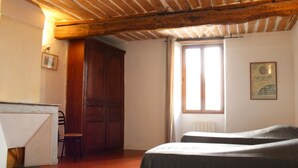 A room with a wooden ceiling, a bed with a striped bedspread, a chair, a wooden wardrobe, and a window with a view of the sky. - Le Ciste - SAINT-JEANNET (SAINT-JEANNET)