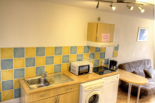 A compact kitchen with a sink, microwave, and washing machine.