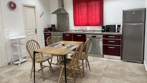 Una cocina compacta con comedor, equipada con un refrigerador de acero inoxidable, cafetera y lavavajillas.
