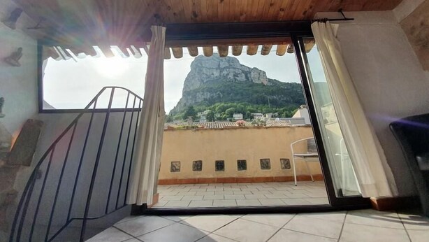 A room with a wooden ceiling, a window with a view of a mountain, and a tiled floor. - La Maison du Chateau (SAINT-JEANNET)