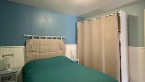 A bedroom with a bed, a nightstand, a lamp, and a wardrobe.