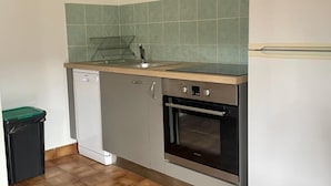 A compact kitchen with a built-in oven, a small sink, and a refrigerator.