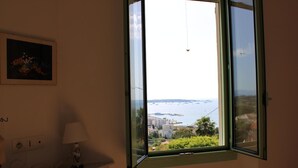 Une pièce avec vue sur une ville côtière, vue à travers une fenêtre ouverte.