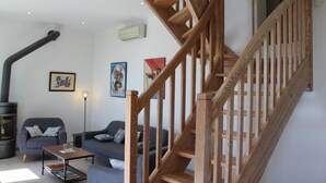 Un salon avec un escalier en bois, une cheminée et deux canapés.