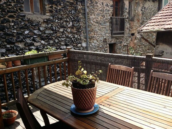 Une table en bois, ornée d’une plante en pot au centre, entourée de chaises en bois.